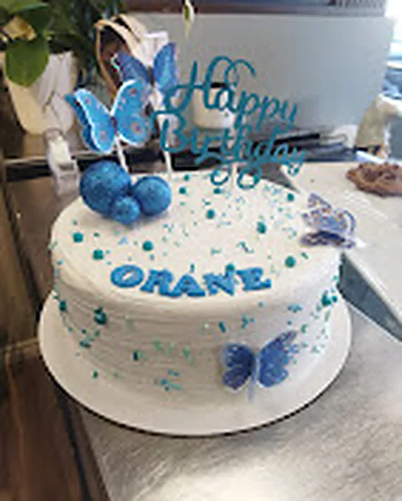 White birthday cake with blue buttercream and butterflies